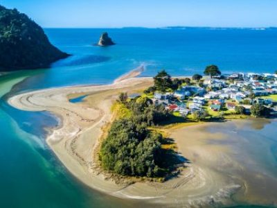 Aerial view on a river mouth with residential suburb on the shore and ocean with small islands on the background. Auckland, New Zealand